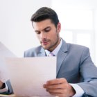 Confident businessman reading documents in office