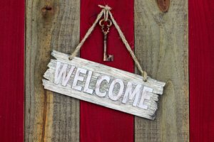 Welcome sign with skeleton key hanging on red wood door