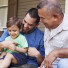 Male Multi Generation Family Sitting On Steps in Front Of House